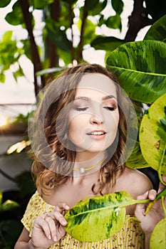 Close-up portrait of young beautiful girl with curly hair summer dress in tropical forest