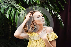 Close-up portrait of young beautiful girl with curly hair summer dress in tropical forest