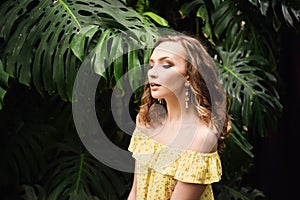 Close-up portrait of young beautiful girl with curly hair summer dress in tropical forest