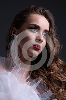 Close up portrait. Young beautiful girl with perfect make up in white veiling dress. Studio shot