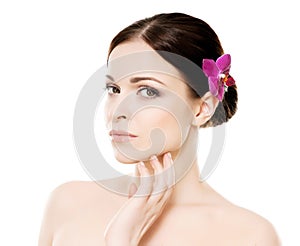 Close-up portrait of young, beautiful and healthy woman with an orchid flower