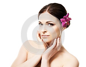 Close-up portrait of young, beautiful and healthy woman with an orchid flower in her hair isolated on white
