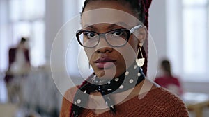 Close-up portrait of young beautiful serious black business woman in eyeglasses looking at camera at office workplace.