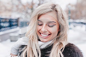 Close-up portrait of young beautiful smiling girl wearing trendy fur winter coat,.Winter time