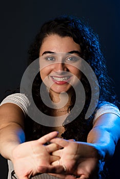 Close-up portrait of young beautiful woman with hands forward, smiling