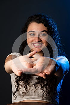 Close-up portrait of young beautiful woman with hands forward, smiling