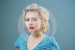 Close up portrait of young beautiful woman with pinup style, hoop earrings, posing on gray Isolated background. Copy