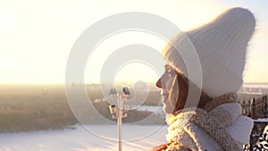 Close-up portrait of young beautiful woman in warm outerwear drinking coffee from paper cup enjoying sunlight standing