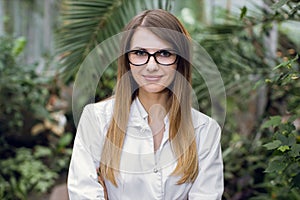 Close up portrait of young Caucasian woman, scientist, botanist, agronomist, wearing glasses and white lab coat, posing
