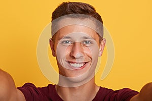 Close up portrait of young charismatic cool magnetic boy looking directly at camera, smiling sincerely, having pleasant facial