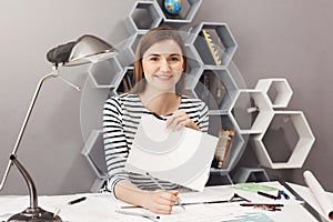 Close up portrait of young cheerful good-looking female freelance architect with dark hair in striped shirt smiling