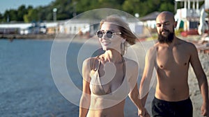 Close up portrait of a young couple strolling along the seaside while on vacation. Caucasian woman with glasses and