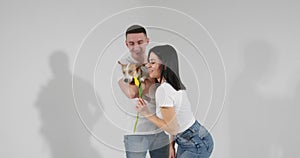 Close up portrait young couple with yellow flowers and dog isolated on white background. Happy dog life. Lovely family