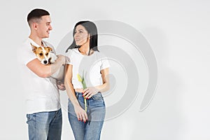 Close up portrait young couple with yellow flowers and dog isolated on white background. lovely couple embracing with