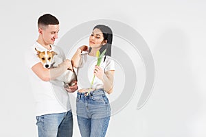 Close up portrait young couple with yellow flowers and dog isolated on white background. lovely couple embracing with