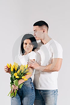 Close up portrait young couple with yellow flowers isolated on white background. lovely couple embracing with dreamy