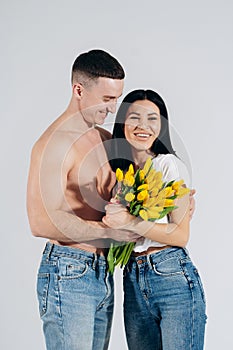 Close up portrait young couple with yellow flowers isolated on white background. lovely couple embracing with dreamy