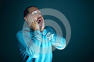 Close up portrait of young crazy scared and shocked man isolated on dark background