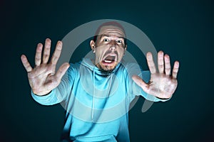 Close up portrait of young crazy scared and shocked man isolated on dark background