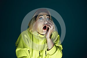 Close up portrait of young crazy scared and shocked woman isolated on dark background