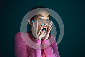 Close up portrait of young crazy scared and shocked woman isolated on dark background