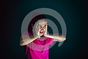 Close up portrait of young crazy scared and shocked woman isolated on dark background