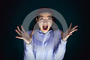 Close up portrait of young crazy scared and shocked woman isolated on dark background