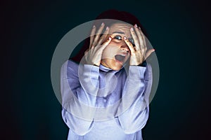 Close up portrait of young crazy scared and shocked woman isolated on dark background