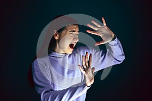 Close up portrait of young crazy scared and shocked woman isolated on dark background