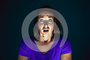 Close up portrait of young crazy scared and shocked woman isolated on dark background