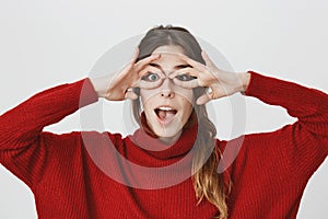 Close up portrait of young emotive girl imitating goggles with hands, looking entertained and funny, isolated on white