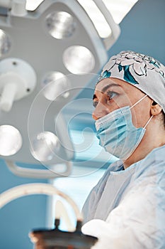 Close-up portrait of young female surgeon doctor at operation theater. Group of surgeons at work. Healthcare, medical