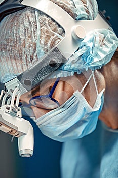 Close up portrait of young female surgeon doctor wearing protective mask and hat during the operation. Healthcare