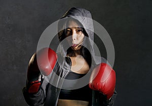 Close up portrait of young fit and healthy Asian Chinese boxer woman in fitness top hoodie and boxing gloves posing cool badass at