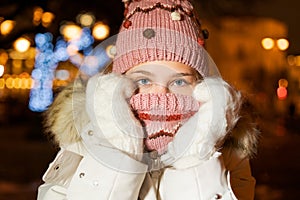 Close-up portrait young girl in knitted hat holds her hands in mittens near