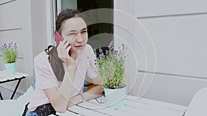 Close-up portrait of a young girl, she is sitting at a table in a cafe and talking on her cell phone.Beautiful young