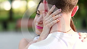 Close-up portrait of a young girl who hugs her beloved guy in a summer park.