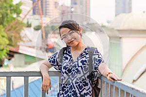 Close up portrait young glasses Asian woman looking at camera with smile, learning railing bridge while traveling in Bangkok