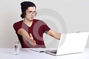 Close up portrait of young handsome man with laptop in hands isolated on white, spreading hands, sees mistake on computer`s scree