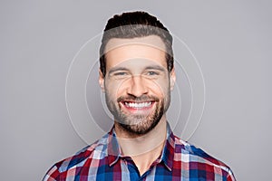 A close up portrait of young happy cheerful young man in checkered shirt in front of gray background