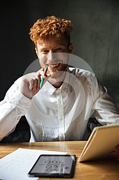 Close-up portrait of young happy readhead curly man, sitting at