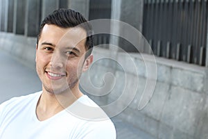 Close up portrait of a young hispanic teenager man looking at camera with a joyful smiling expression, against urban background