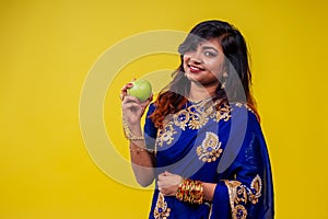 Close up portrait of a young Indian brunette woman with traditional blue sari in studio in yellow copy space background