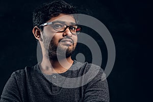 Close-up portrait of a young Indian guy in eyewear and casual clothes looking at a camera in studio
