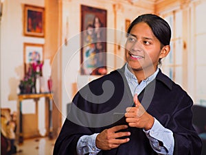 Close up portrait of young indigenous man wearing hat and poncho using cell phone