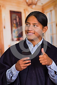 Close up portrait of young indigenous man wearing hat and poncho using cell phone