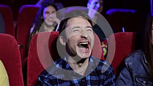 Close-up portrait of a young laughing man in a movie theater.