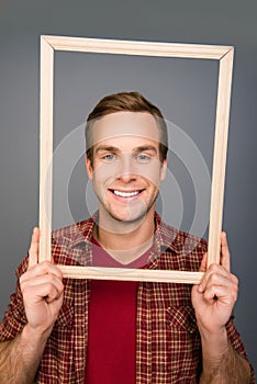Close up portrait of young man with beaming smile and wooden frame