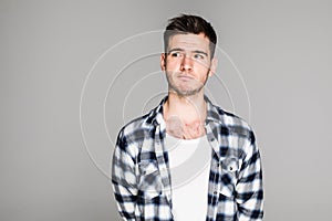 Close up portrait of a young man with a confused, thinking face isolated on gray background