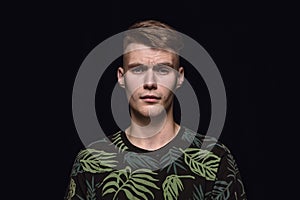 Close up portrait of young man isolated on black studio background